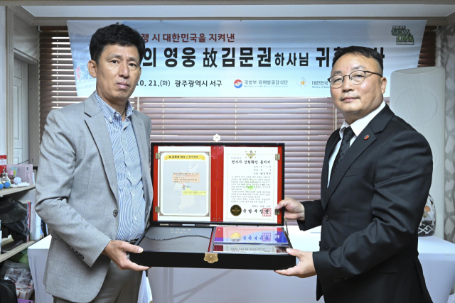 조해학 국방부유해발굴감식단장 직무대리(육군 중령)가 21일 고(故) 김문권 하사의 유가족 대표인 친조카 김대중씨에게 호국의 얼 함을 전달하고 있다. 사진 제공=국방부