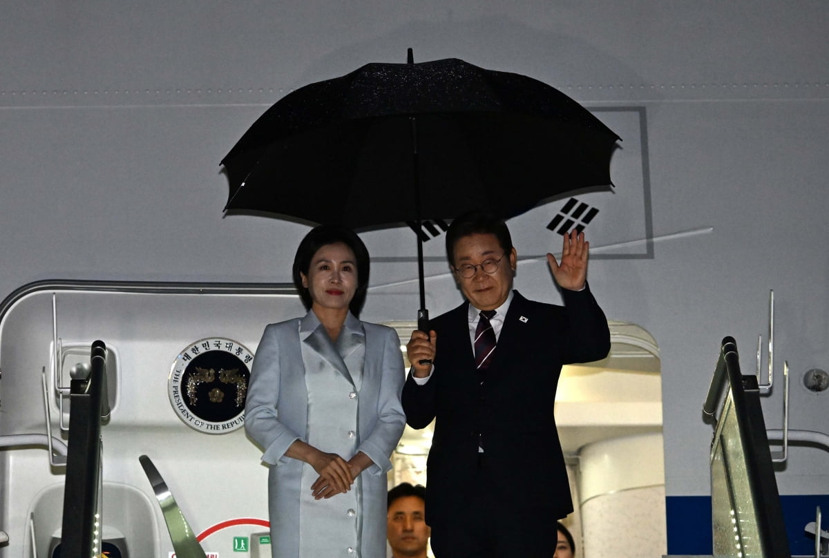 이재명 대통령과 부인 김혜경 여사가 17일(현지시간) 주요 7개국(G7)정상회의 일정을 마치고 캐나다 앨버타주 캘거리국제공항에서 공군 1호기에 탑승하며 손 인사를 하고 있다.  / 사진=대통령실사진기자단
